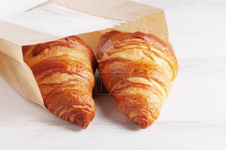 Foto de Croissants en una bolsa de papel en un primer plano de mesa ligera - Imagen libre de derechos