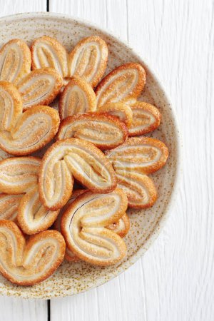 French Palmiers Cookies - Elefantenohrkekse in einem Teller auf weißem Holzhintergrund, Ansicht von oben
