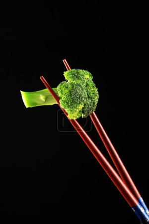 Photo for Food Broccoli on a Chop Sticks on Black Background - Royalty Free Image
