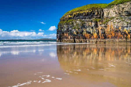 Foto de Pintoresco acantilado que se refleja en la arena mojada en Ballybunion Beach, Condado de Kerry, Irlanda. Uno de los puntos de descubrimiento en la ruta costera del Atlántico. - Imagen libre de derechos