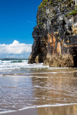 Téléchargez les photos : Vagues océaniques et falaise pittoresque reflétant dans le sable mouillé à Ballybunion Beach, comté de Kerry, Irlande. L'un des points de découverte sur Wild Atlantic Way. - en image libre de droit