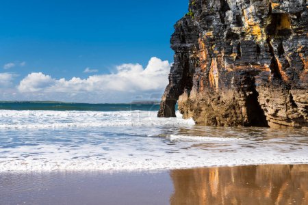 Téléchargez les photos : Vagues océaniques et falaise pittoresque reflétant dans le sable mouillé à Ballybunion Beach, comté de Kerry, Irlande. L'un des points de découverte sur Wild Atlantic Way. - en image libre de droit