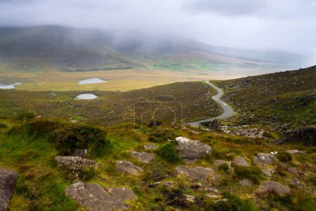 Photo for Scenic view of mountains and road from Conor Pass on Dingle peninsula on overcast day in County Kerry, Ireland. - Royalty Free Image