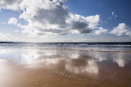 Téléchargez les photos : Nuages dramatiques se reflétant dans le sable humide de la plage de Ballybunion dans le comté de Kerry, en Irlande. L'un des nombreux paysages pittoresques de Wild Atlantic way. - en image libre de droit