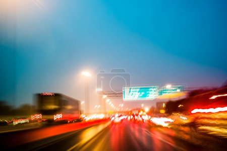 Téléchargez les photos : Conduite sur autoroute achalandée à l'heure de pointe, flou abstrait de mouvement avec des sentiers lumineux créés par la photographie de longue exposition - en image libre de droit