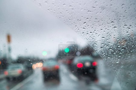 Téléchargez les photos : Voitures conduisant par mauvais temps avec brouillard et forte pluie sur la rue de la ville vu à travers le pare-brise - en image libre de droit