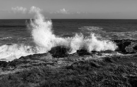 Powerful waves crushing over rocks on Atlantic coast of Ireland, in black and white.
