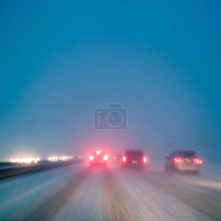 Foto de Conducir en malas condiciones climáticas con nieve en la carretera nocturna, desenfoque de movimiento en cámara de larga exposición - Imagen libre de derechos