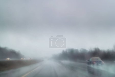 Téléchargez les photos : Voitures conduisant dans des conditions météorologiques défavorables avec brouillard et fortes pluies sur l'autoroute, longue exposition dans le flou du mouvement de la caméra - en image libre de droit
