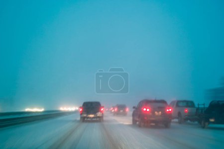 Téléchargez les photos : Conduite dans des conditions météorologiques défavorables avec neige sur l'autoroute de nuit, longue exposition dans le flou du mouvement de la caméra - en image libre de droit