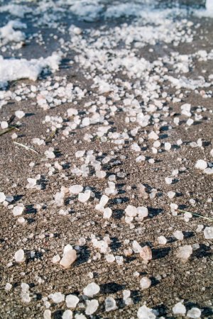 Téléchargez les photos : Gros plan sur le sel gemme sur le trottoir appliqué sur la glace fondante et la neige - en image libre de droit
