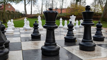 Foto de Un gran tablero de ajedrez en un parque. De cerca en peones negros reina y rey. - Imagen libre de derechos