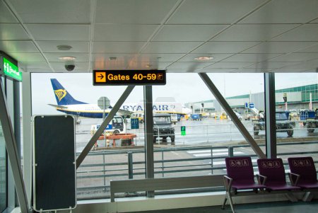 Foto de Empty airport gate waiting hall of a modern airport with airplane parked outside the window. Stansted, England - January 1, 2023. - Imagen libre de derechos