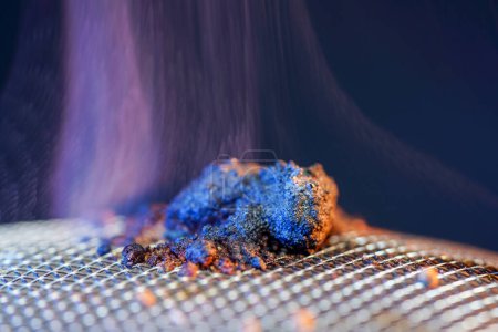 Foto de Especia para fumar en una rejilla de alambre fino brilla, fuma y quema - Imagen libre de derechos