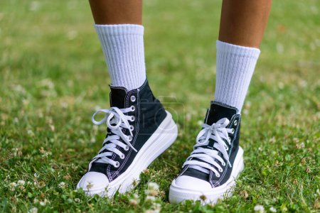 Téléchargez les photos : Baskets noires élégantes avec des chaussettes de genou blanches sur un fond d'herbe - en image libre de droit