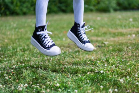 Foto de Elegantes zapatillas negras con calcetines blancos de rodilla contra el fondo de hierba en vuelo - Imagen libre de derechos