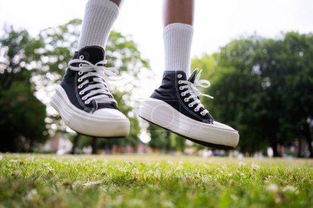 Téléchargez les photos : Baskets noires élégantes avec des chaussettes de genou blanches sur le fond d'herbe en vol - en image libre de droit