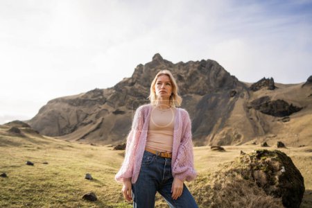 Téléchargez les photos : Fille de la mode dans une veste violette pose contre dans les montagnes en Islande - en image libre de droit