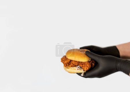 Photo for A craft juicy burger with cheese is held in the hands of a chef in black gloves on white background - Royalty Free Image
