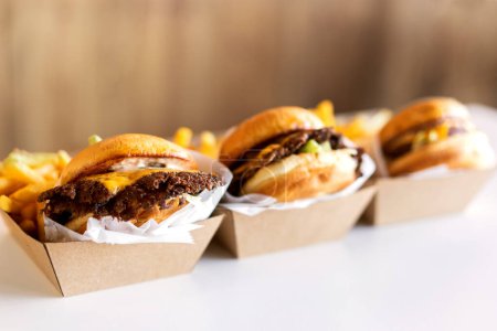 Téléchargez les photos : Burgers avec des frites reposent sur une table sur un fond blanc dans des boîtes de livraison - en image libre de droit