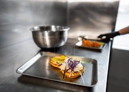 Foto de Hamburguesa artesanal jugosa con queso es hecha por un chef con guantes negros en el fondo de la cocina. - Imagen libre de derechos