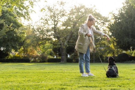 Téléchargez les photos : Une fille de quarante ans joue dans le parc avec son chien, un bouledogue français - en image libre de droit