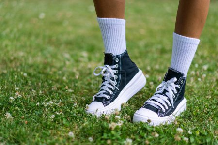 Foto de Elegantes zapatillas negras con calcetines blancos de rodilla sobre un fondo de hierba - Imagen libre de derechos