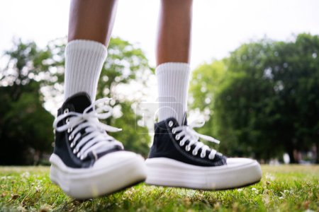 Téléchargez les photos : Baskets noires élégantes avec des chaussettes de genou blanches sur un fond d'herbe - en image libre de droit