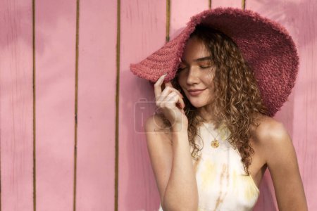 Foto de Moda hermosa chica en un sombrero posando sobre un fondo rosa en casa - Imagen libre de derechos