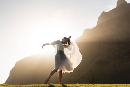 Téléchargez les photos : Fille dansant en robe au coucher du soleil en Islande - en image libre de droit