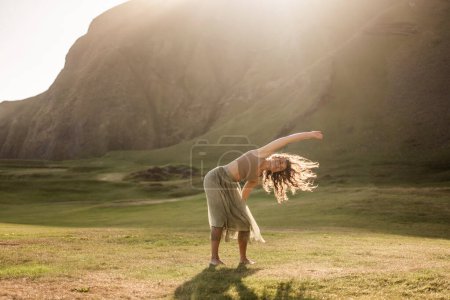 Téléchargez les photos : Fille dansant dans une robe légère au coucher du soleil en Islande - en image libre de droit