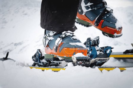 Foto de Close-up of freeride ski boots on snow. Skitour concept. Used worn boots on a male skier against the background of a glacier in cloudy weather in the mountains. - Imagen libre de derechos