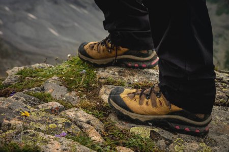 turistas pies en la roca de la cima de la montaña, en zapatos de trekking para una caminata, primer plano.