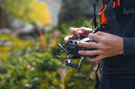 Téléchargez les photos : Gros plan d'un mans tenant une télécommande pour contrôler un drone de course FPV. piloter un aéronef sans pilote. - en image libre de droit