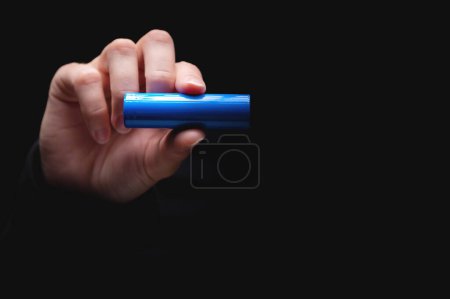Téléchargez les photos : Batterie lithium-ion pour la puissance dans une main humaine, sur un fond noir. Femme main montrant une batterie, gros plan, maquette. - en image libre de droit