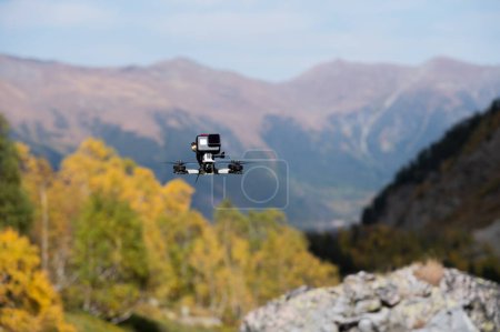 FPV-Drohne schwebt in der Luft und filmt einen Wald in den Bergen mit einer an der Drohne befestigten Actionkamera.
