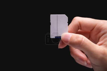 Nuevas tarjetas de memoria micro SD rápidas y adaptador de tarjeta SD en la mano sobre fondo negro.
