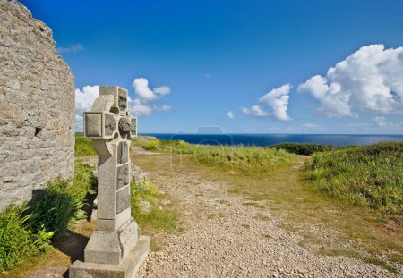 Photo for Celtic cross near the remains of an old medieval tower on Pointe du Raz. Brittany, France - Royalty Free Image