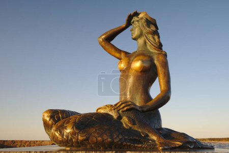 Téléchargez les photos : USTKA - 02 JUIN 2023 : Une célèbre statue de la sirène à l'entrée du port au coucher du soleil Ustka, Pologne. - en image libre de droit