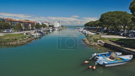 Photo for Grado, Grado, Friuli Venezia Giulia Italy-15 May 2023: Cityscape of Grado, Italy. View of a canal with motorboats on the water, modern buildings and Alps in background. - Royalty Free Image