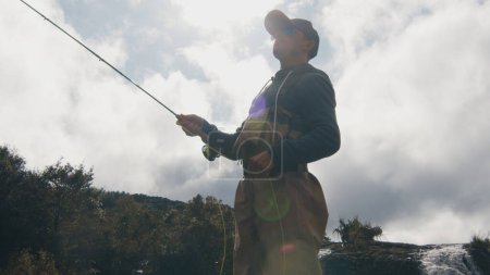Foto de Pesca con mosca. Pescador en vadeadores pescando en el río rápido - Imagen libre de derechos