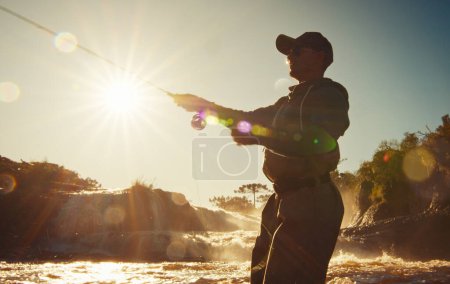 Téléchargez les photos : Pêche à la mouche. Pêcheur dans les échassiers pêchant sur la rivière rapide - en image libre de droit