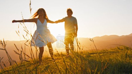 Téléchargez les photos : Homme et femme dansent sur la prairie d'été avec de l'herbe au lever du soleil - en image libre de droit
