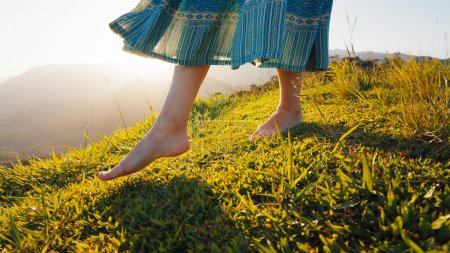 Foto de Mujer en vestido camina sobre la hierba descalza - Imagen libre de derechos
