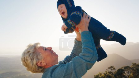 Téléchargez les photos : Femme âgée joue avec bébé bébé en plein air - en image libre de droit