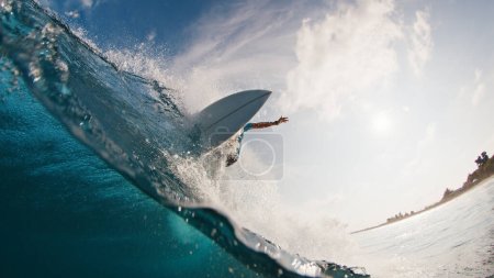 Photo for Pro surfer rides the wave. Young man surfs the ocean wave in the Maldives and aggressively turns on the lip. Splitted above and underwater view - Royalty Free Image