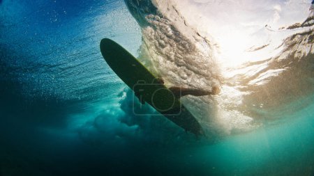 Foto de Surfista bajo el agua. Un joven en el océano. Surfista remar la tabla de surf para pasar la ola en las Maldivas - Imagen libre de derechos
