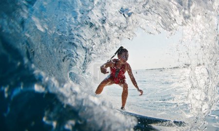 Foto de La chica surfista monta la ola. Mujer en traje rojo surfea la ola oceánica en las Maldivas y consigue barrido - Imagen libre de derechos