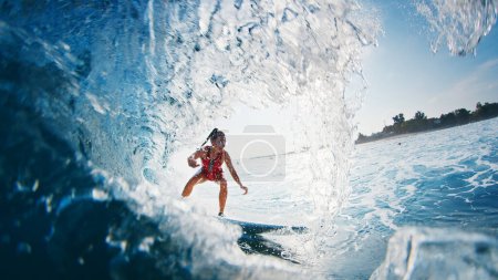 Foto de La chica surfista monta la ola. Mujer en traje rojo surfea la ola oceánica en las Maldivas y consigue barrido - Imagen libre de derechos