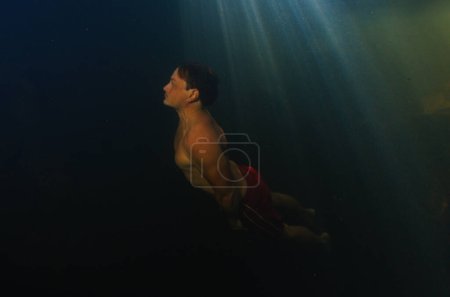 Photo for Young man free dives in the lake located in a forest - Royalty Free Image